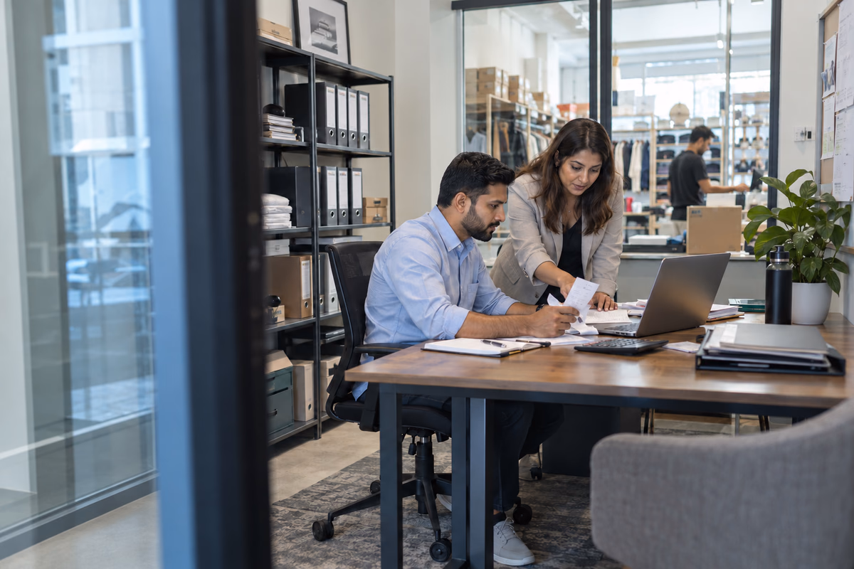 Business owner and accountant reviewing receipts and bookkeeping in a small UAE retail office