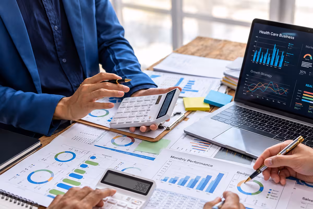 Reviewing financial reports with calculators and a laptop
